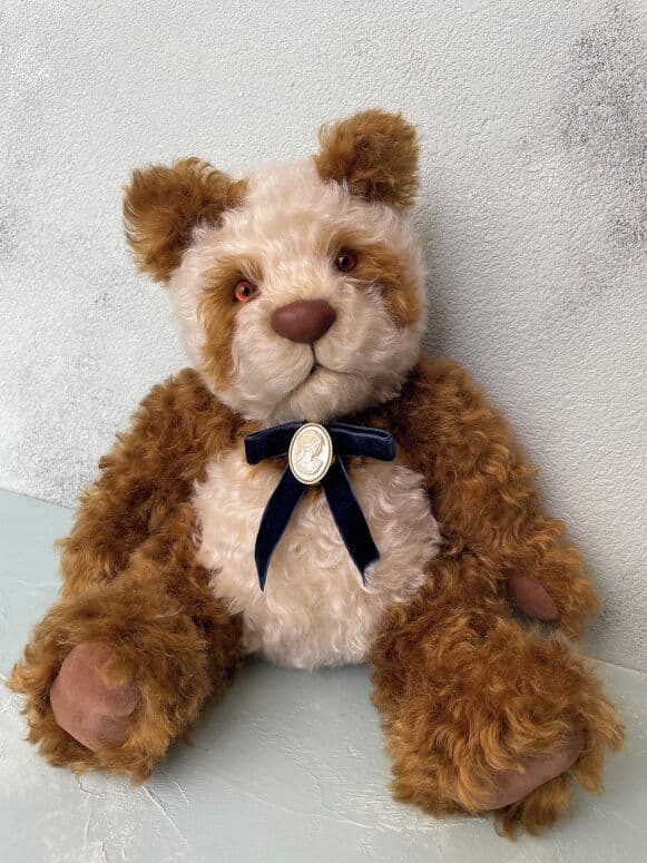 Toto, a cinnamon-and-cream panda artist bear, seated full length